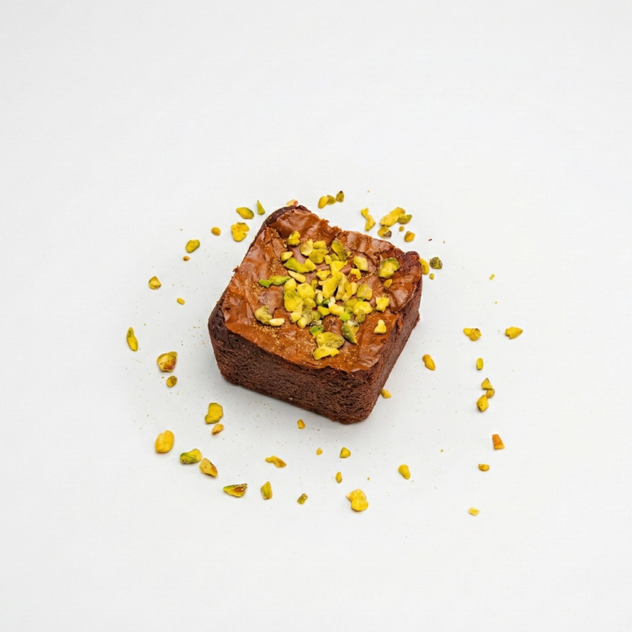 Square piece of Brownie with yellow toppings on a white background

