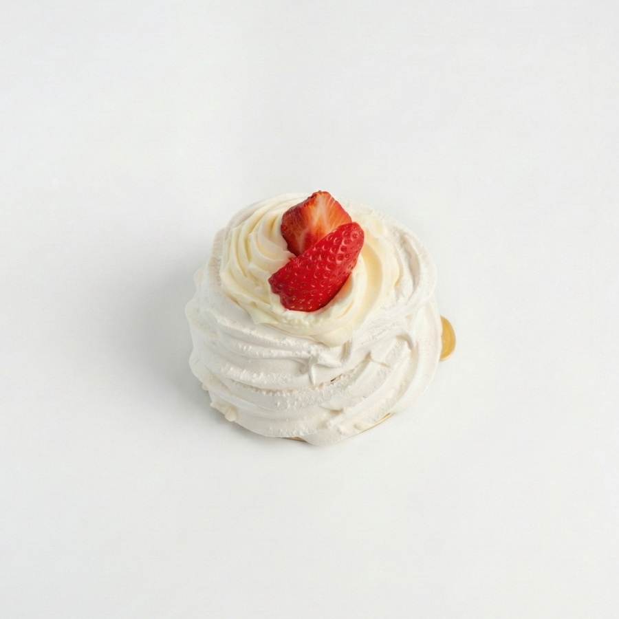 Small Pavlova dessert with whipped cream and a strawberry on a light gray background

